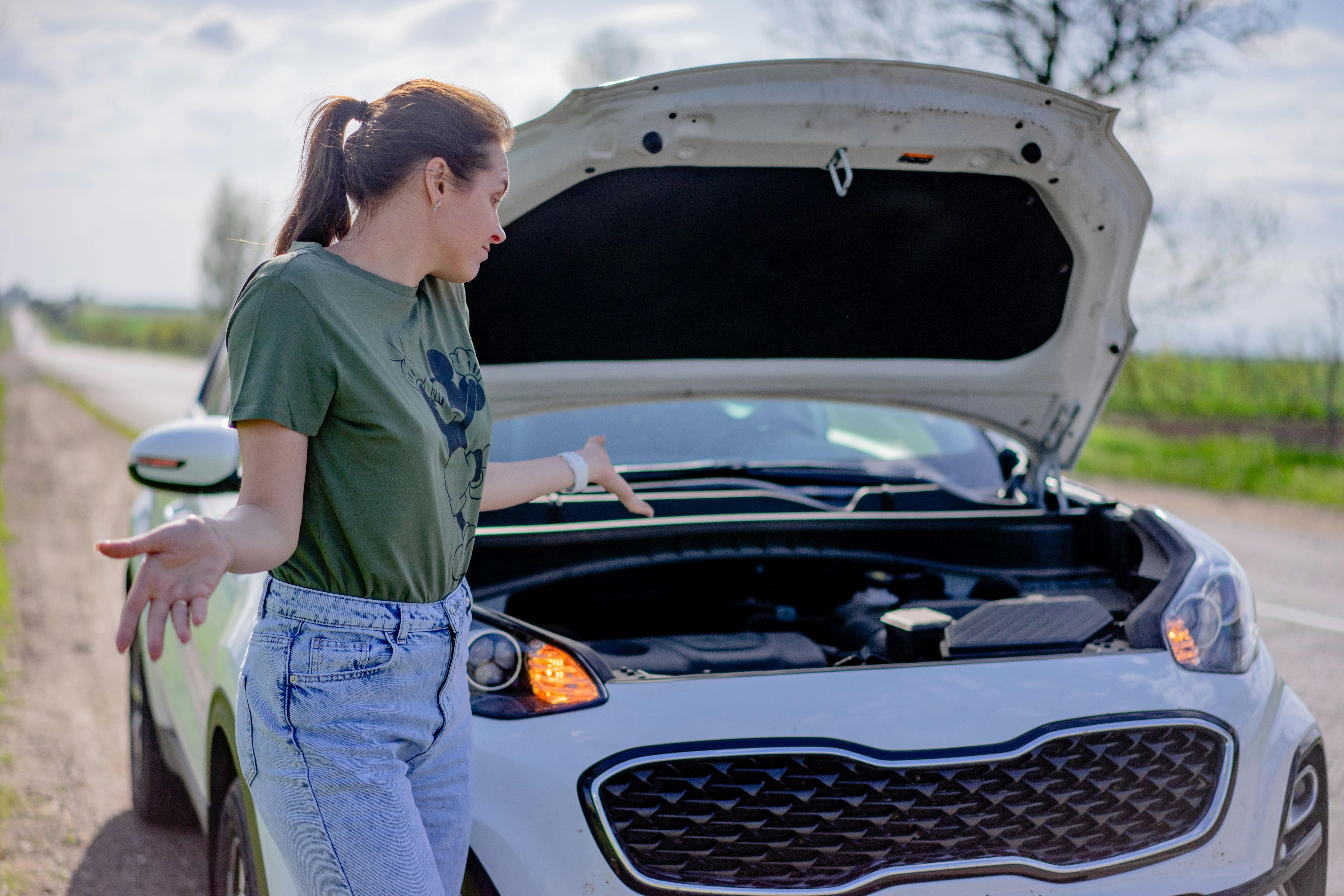 Woman with hands in the air in front of broken down car